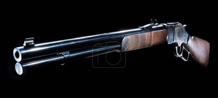 Traditional Old West style lever action rifle with a wood stock and color casehardened receiver on a black background in a studio shot.