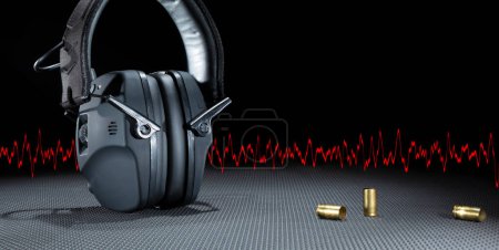 Photo for Room for text next to electronic hearing protection for shooting with empty ammo and a red sine wave - Royalty Free Image