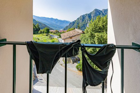 Photo for Swimming costume stretched out at the window in a mountain setting in the south of France in the Alpes Maritimes in Provence. Maillot de bain tendu a la fenetre dans un decor de montagne du sud de la France dans les Alpes Maritimes en Provence. - Royalty Free Image
