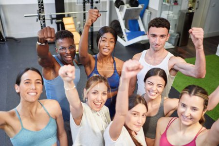 Photo for Multicultural fitness group looking at the camera smiling and with fist in the air - Royalty Free Image