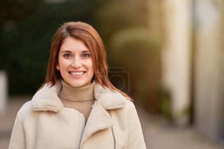 Foto de Retrato de una mujer feliz mirando a la cámara y sonriendo mientras está al aire libre. - Imagen libre de derechos