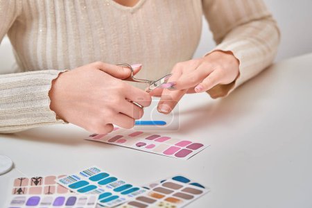 Photo for Woman cutting and shaping her nails after applying nail decal. Manicure and beauty concept. - Royalty Free Image