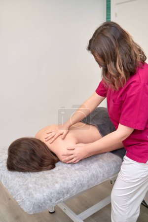 Téléchargez les photos : Physiothérapeute féminine qualifiée soulageant la douleur au dos avec des techniques de massage - en image libre de droit