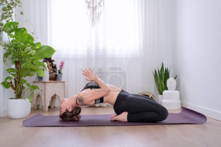 Photo for Woman meditating in Matsyasana pose on a yoga mat at home. Sports concept. - Royalty Free Image