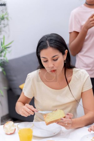 Téléchargez les photos : Femme étalant du beurre sur une tranche de gâteau pour son repas du matin. - en image libre de droit