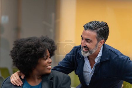 Téléchargez les photos : Une femme et un homme partagent un moment de légèreté, riant ensemble lors d'une conversation décontractée au bureau. - en image libre de droit