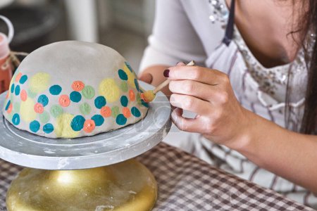 Artist applies vibrant polka dots to a ceramic bowl on a turntable, showcasing intricate hand detailing