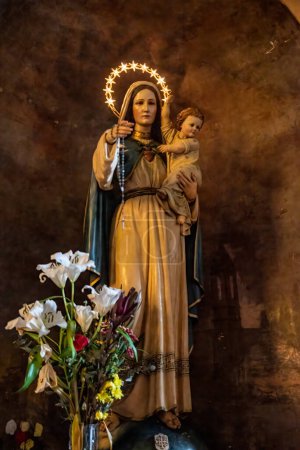statue de la madone avec bébé Jésus et fleurs à ses pieds