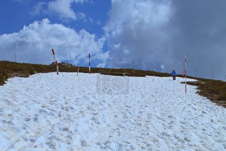 Téléchargez les photos : Deux enfants descendent du sommet de La Bola del Mundo dans la Sierra de Guadarrama, Espagne. Haut avec de la glace au printemps et avec les marqueurs d'épaisseur de neige qui indiquent le chemin quand il y a de la neige. - en image libre de droit