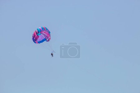 Photo for Water activities parachute over the Ionian Sea in Marina di Salve, Puglia, Italy. Couple enjoying a trip on Parasailing, a parachute pulled by a motorboat. - Royalty Free Image