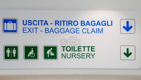 Photo for Information sign at the Bari-Palese airport, Aeroporto Internazionale di Bari-Karol Wojtyla, Italy. Signage for the location of the toilet, baggage claim and departure in English and Italian. - Royalty Free Image