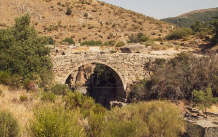 Foto de Puente romano sobre el río Barbellido en Navacepeda de Tormes en Ávila, España. Puente de piedra que cruza el charco o piscina conocido como Poza de las Paredes. - Imagen libre de derechos