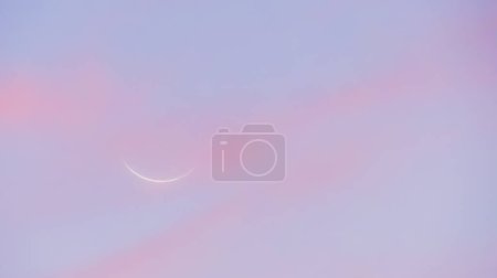 Neumond bei Sonnenuntergang. Himmel aus rosa und bläulichen Tönen mit dem Profil des Neumondes im Hintergrund.