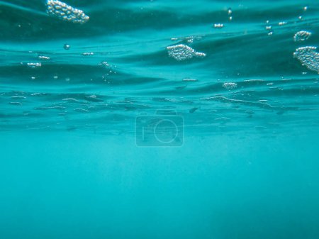 Foto de Burbujas azules profundas y peces bajo la superficie del agua. Fotografía de la superficie del agua en el mar Mediterráneo tomada desde abajo. - Imagen libre de derechos