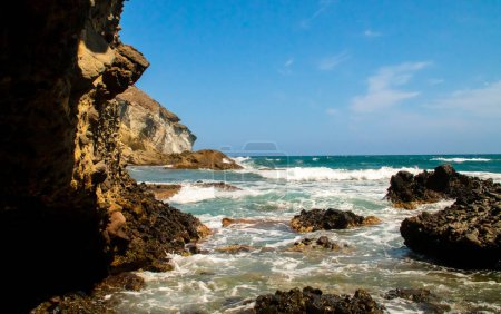Foto de Acantilados, rocas y olas en la costa del mar Mediterráneo en un día despejado. Costa de Cabo de Gata, Cala de los Amarillos en verano, Almería, España. - Imagen libre de derechos