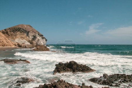 Foto de Acantilados, rocas y olas en la costa del mar Mediterráneo en un día despejado. Costa de Cabo de Gata, Cala de los Amarillos en verano, Almería, España. - Imagen libre de derechos