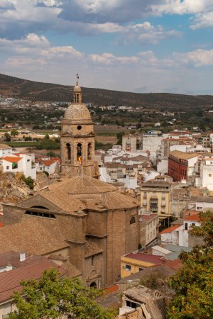 Blick auf die Hauptkirche Santa Maria de la Encarnacion vom Aussichtspunkt Isabel I de Castilla in Loja. Blick auf den Glockenturm und das Dach umgeben von Wohnhäusern in Loja, Spanien.
