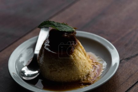 Photo for Homemade egg flan with caramel sauce and mint on white plate - Royalty Free Image