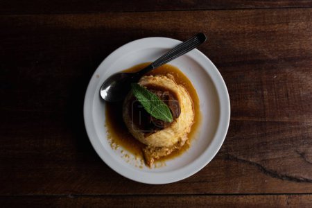 Téléchargez les photos : Vue du dessus du flan d'oeuf maison avec sauce caramel et menthe sur assiette blanche - en image libre de droit
