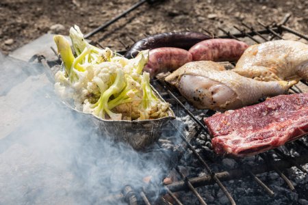 Téléchargez les photos : Saucisses, steaks, cuisses de poulet et chou-fleur grillés à l'extérieur - en image libre de droit