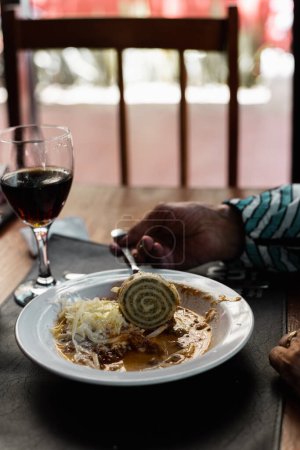 Téléchargez les photos : Plan vertical d'une personne mangeant de la pâte roulée "raviolon" avec garniture aux légumes et sauce - en image libre de droit