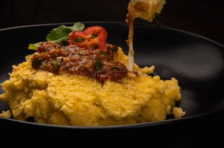 Photo for Black plate of polenta with tomato sauce and melted cheese flour - Royalty Free Image
