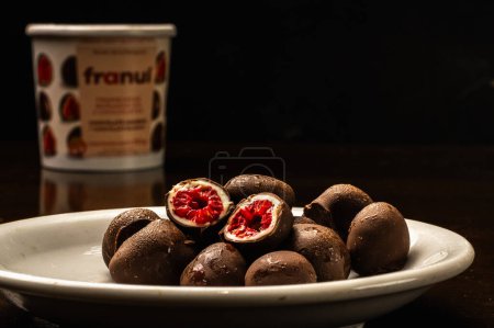Téléchargez les photos : Gros plan de framboise trempée dans deux couches de biscuits au chocolat noir et blanc - en image libre de droit
