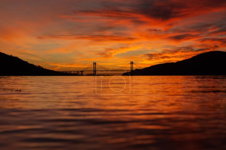 Téléchargez les photos : Vue sur le pont de Rande et l'estuaire de Vigo depuis la plage de Cesantes dans un magnifique coucher de soleil orange en Galice - en image libre de droit