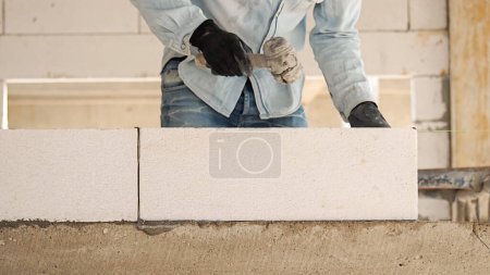 Photo for Construction workers are making white lightweight concrete blocks that are better than cement bricks, popular in the construction of homes and public buildings. - Royalty Free Image