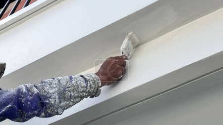 Ein Arbeiter streicht mit einem Pinsel die Wände des Hauses mit einer Grundierung.