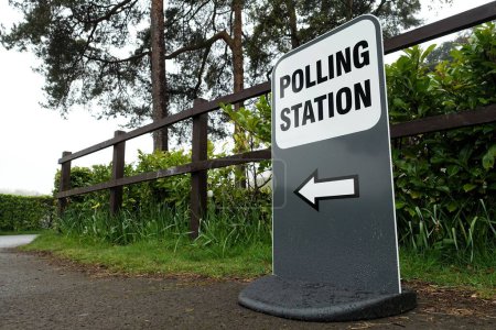 Señal de dirección al centro de votación del Reino Unido junto a la valla