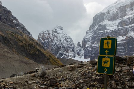 Señal de sendero que marca dos caminos, uno para excursionistas y otro para caballos. Con el fondo de las montañas rocosas canadienses cubiertas de nieve.
