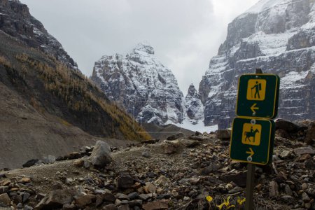 Señal de sendero que marca dos caminos, uno para excursionistas y otro para caballos. Con el fondo de las montañas rocosas canadienses cubiertas de nieve.