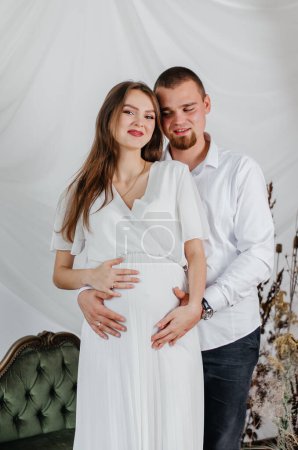 Photo for A pregnant girl and her husband stand in an embrace - Royalty Free Image