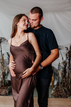 Téléchargez les photos : A young man hugs a pregnant woman - en image libre de droit