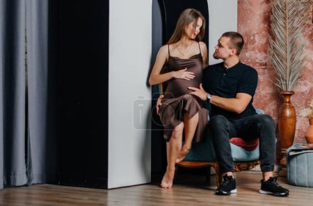 Photo for A pregnant woman is sitting on an armchair with a man - Royalty Free Image