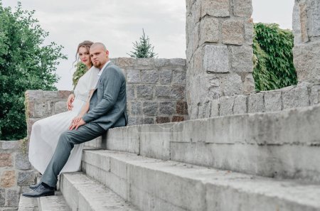 Photo for The bride and groom are sitting on the stairs - Royalty Free Image