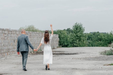 Photo for The bride and groom walk down the road - Royalty Free Image