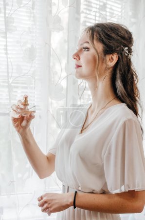 a bride in a wedding dress applies perfume