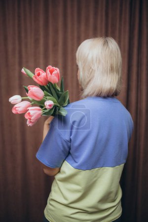 Photo for A woman holding a bouquet of tulips with a blue shirt on - Royalty Free Image