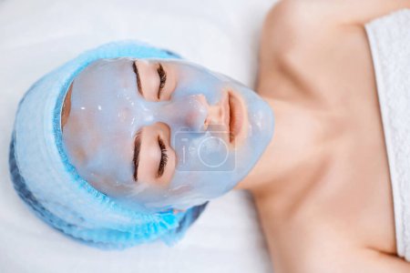 hermosa mujer con máscara de alginato azul en la cara en el salón de spa. primer plano