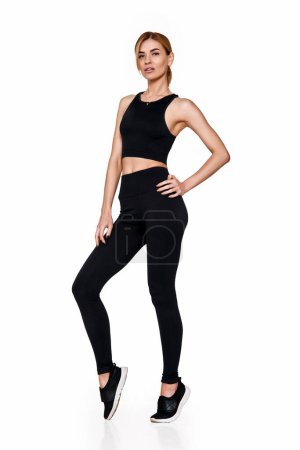 Photo for Sporty blonde woman in sportswear training . slim girl in black sport leggings and running shoes on white background - Royalty Free Image