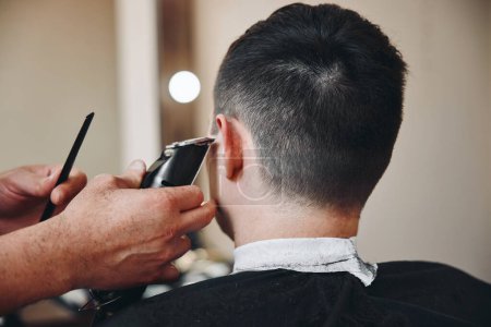 Téléchargez les photos : Barber rasage bel homme caucasien dans le salon de coiffure. - en image libre de droit