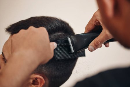 Foto de Cortar el cabello con máquina de esquiladora eléctrica en el hombre caucásico en la peluquería. primer plano - Imagen libre de derechos