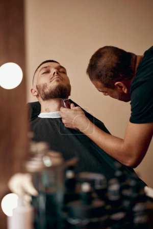 Foto de Peluquero afeitado hombre barbudo guapo en la peluquería. - Imagen libre de derechos