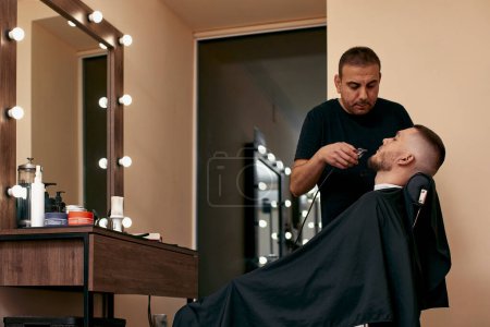 Foto de Peluquero afeitado hombre barbudo guapo en la peluquería. - Imagen libre de derechos