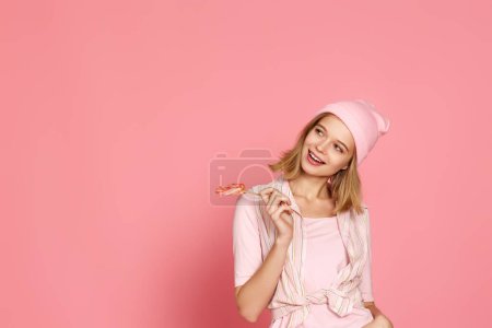 Photo for Beautiful blonde woman holding candy on pink background. copy space - Royalty Free Image