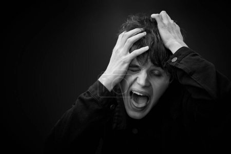 Foto de Portrait of crazy young man yelling with a violent or desperate face and grimacing . black and white - Imagen libre de derechos