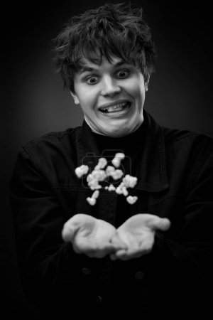 Foto de Portrait of crazy young man throwing up popcorn and grimacing . black and white - Imagen libre de derechos