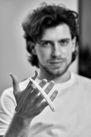 Téléchargez les photos : Barber hand testing the sharpness of blade before cutting. black and white - en image libre de droit